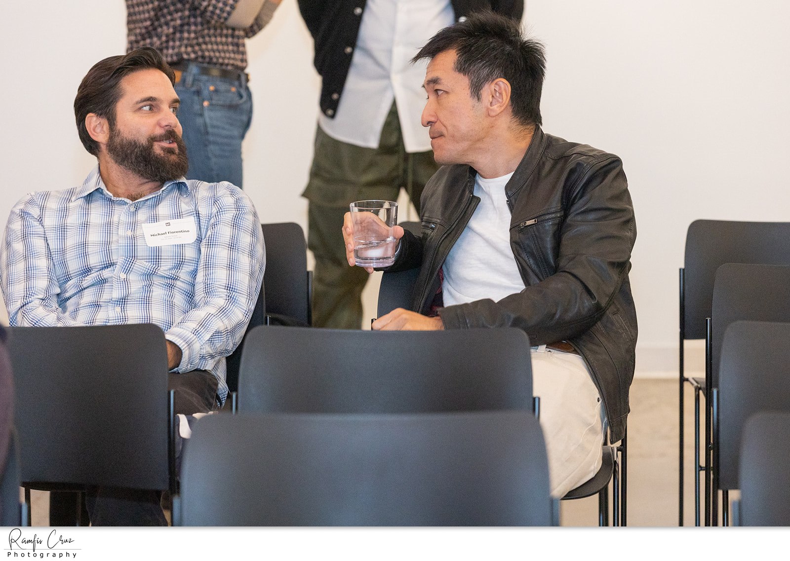 Two attendees talking between rows of seats before a talk